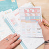 Home Planner  on counter with lady applying sticker from Sticker Book