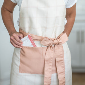 Lady wearing a Kitchen Apron Collection in pink plaid with recipe card in pocket