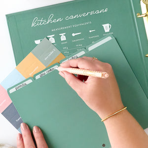 green recipe binder with tab being written on