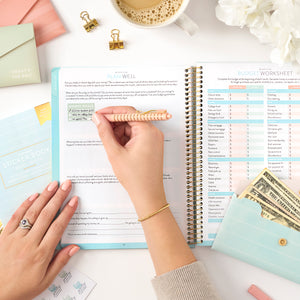 writing in money planner with gel pen on top of a money planner sticker